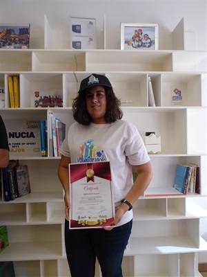 Marta Ruíz con su diploma de reconocimiento a su labor altruista en l'Escola d'Estiu